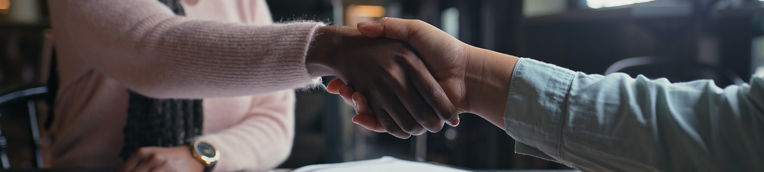Business people, handshake and documents with meeting for interview, hiring or recruiting at cafe. Closeup, employer and candidate shaking hands for career opportunity or partnership at coffee shop - stock photo